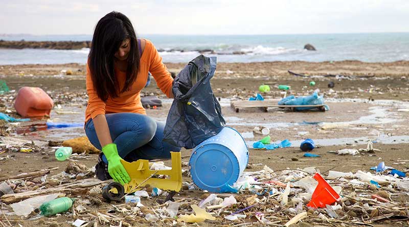 Young woman picking up plastic on a beach