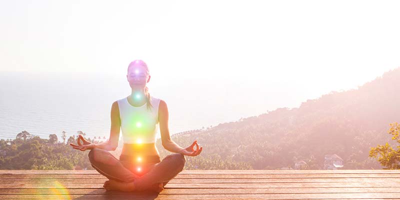 Young woman meditating on wooden platform