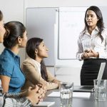 A young woman giving a presentation to three other women