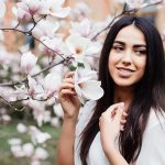 Young woman holding spring flowers blossoming on a magnolia tree