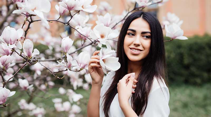 Young woman holding spring flowers blossoming on a magnolia tree