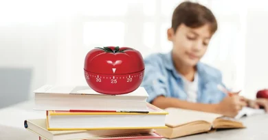 Boy studying at his desk with a pomodoro timer resting on top of his books.