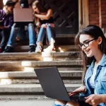 College girl smiling and working on her laptop