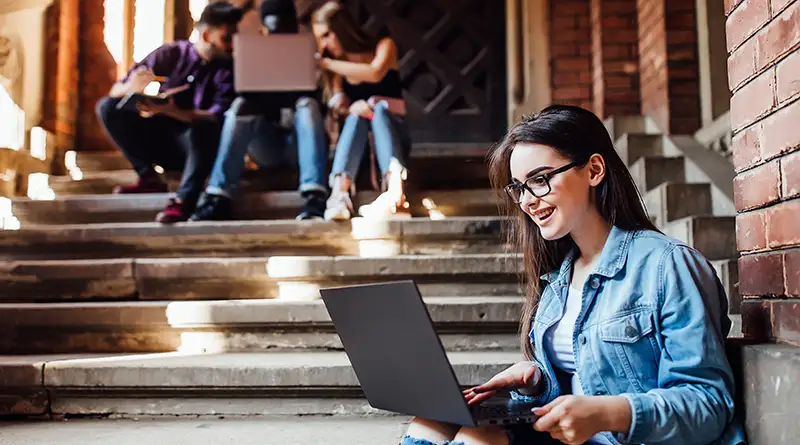 College girl smiling and working on her laptop