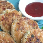 Plate with leftover rice cutlets with a bowl of tomato sauce