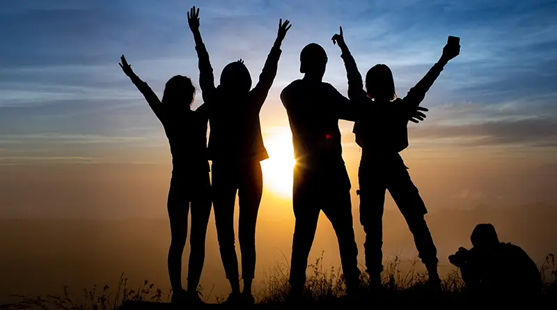 Silhouette of friends with arms in the air