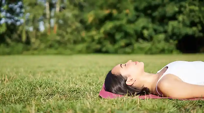 Young woman lying down and sleeping on green grass