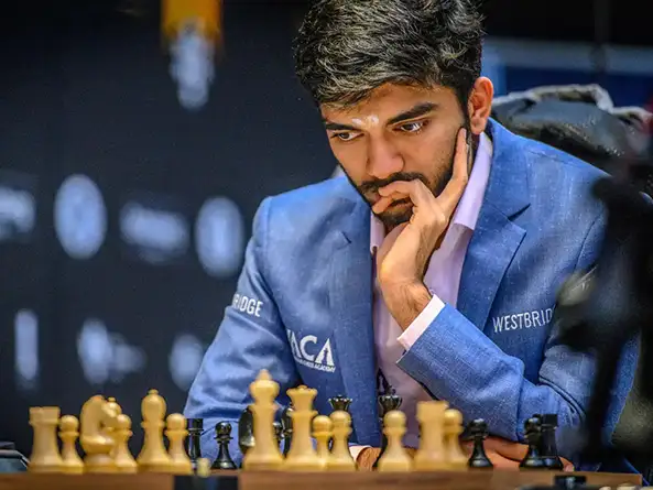 Gukesh Dommaraju staring at the chess pieces on a chess board