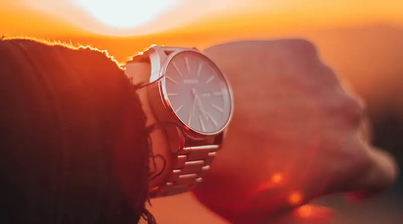 Wristwatch on man's hand at sunset