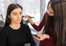 Female makeup artist applying blusher to a young female model