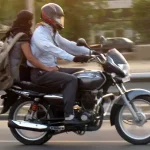 Motorbike rider with helmet and female pillion rider without helmet