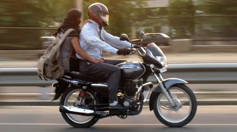 Motorbike rider with helmet and female pillion rider without helmet