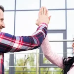 Happy young man and woman giving each other a high five