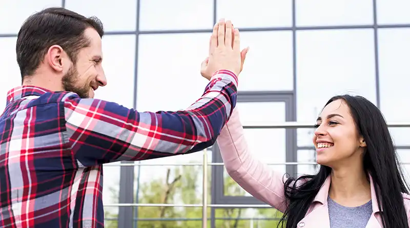 Happy young man and woman giving each other a high five