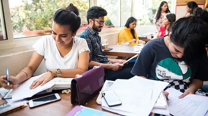 Young people studying and writing while seated at desks