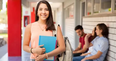 Young woman carrying books and a backpack and smiling